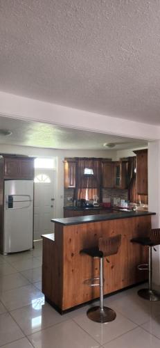 uma cozinha com armários de madeira e um balcão com bancos de bar em vacation home em Roseau