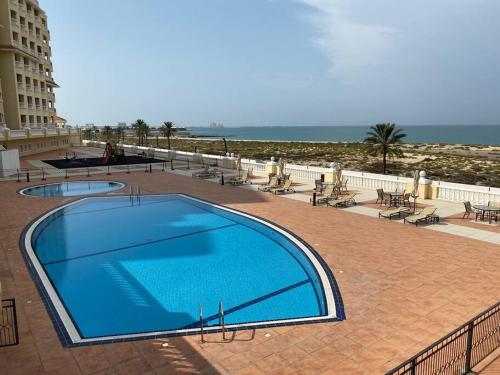 a large blue swimming pool next to a beach at Relaxing, Swimming and Golfing in Al Hamra Village in Ras al Khaimah