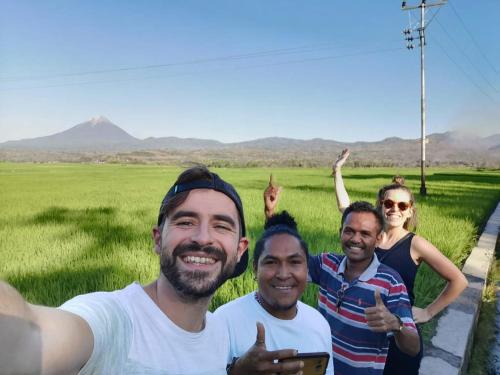 a group of men posing for a picture in front of a field at Kristian Homestay in Bajawa