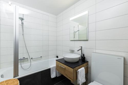 La salle de bains blanche est pourvue d'un lavabo et d'une douche. dans l'établissement Apartment La Foret, à Riddes