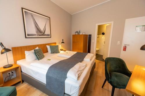 a bedroom with a large bed and a chair at Comfort Hotel tom Kyle in Kiel