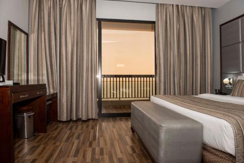 a hotel room with a large bed and a window at Palma Beach Resort & Spa in Umm Al Quwain