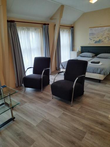 een hotelkamer met 2 stoelen en een bed bij Logement 'De witte klok' in Oude Bildtzijl
