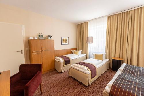 a hotel room with two beds and a chair at Comfort Hotel tom Kyle in Kiel