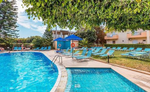 a swimming pool with blue chairs and a building at Castro Hotel in Amoudara Herakliou