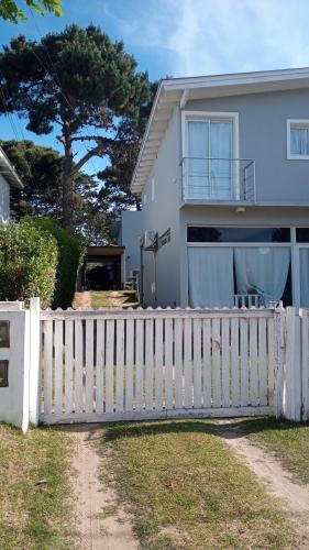 una cerca blanca frente a una casa blanca en Departamento para 4 primer piso en Valeria del Mar