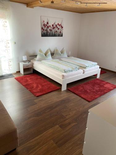 a bedroom with a large bed with red rugs at Ferienwohnung Rauch in Pretzfeld