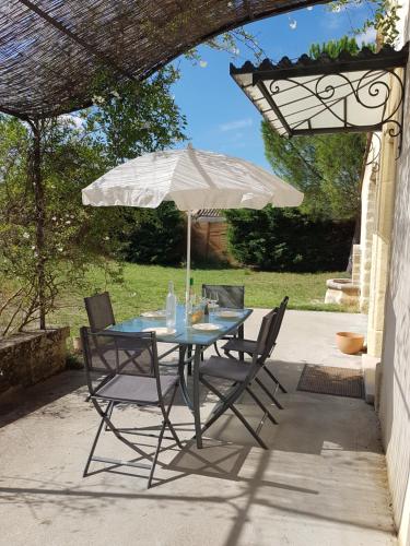una mesa y sillas con una sombrilla en el patio en Maison de charme avec bassin de nage 