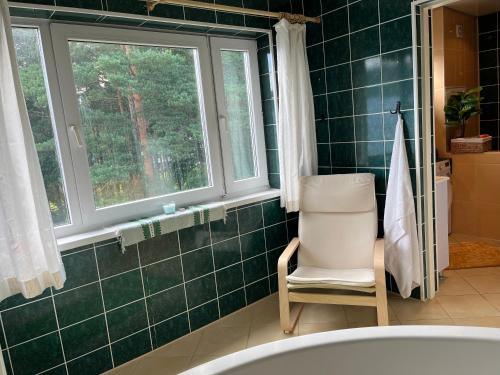 een groene betegelde badkamer met een stoel en een raam bij Cosy Appartment. Püssi town in Pyussi