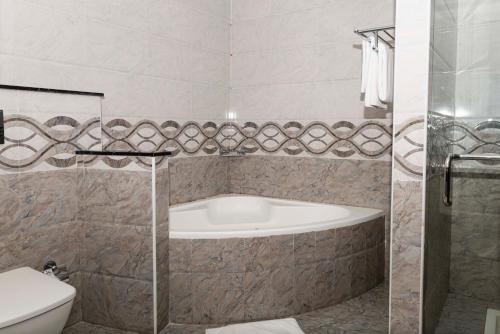 a bathroom with a bath tub and a toilet at Palma Beach Resort & Spa in Umm Al Quwain
