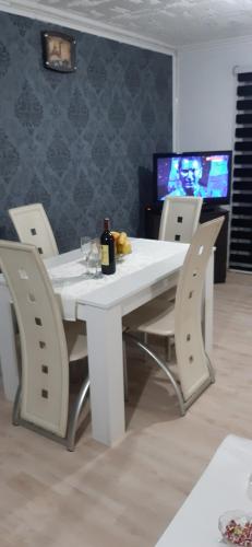 una mesa blanca con sillas y una botella de vino en Vila city, en Bijeljina