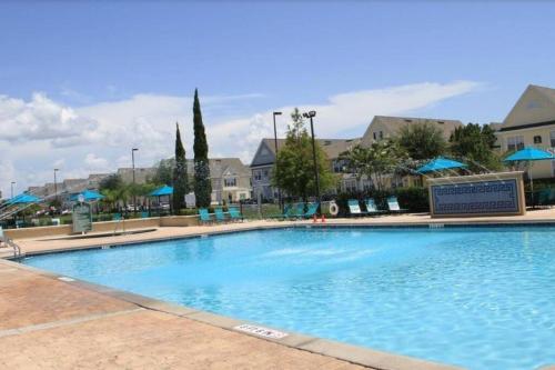 a large swimming pool at a resort with blue umbrellas at Family Friendly 3BR near Disney in Kissimmee