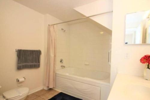 a white bathroom with a tub and a toilet at Family Friendly 3BR near Disney in Kissimmee