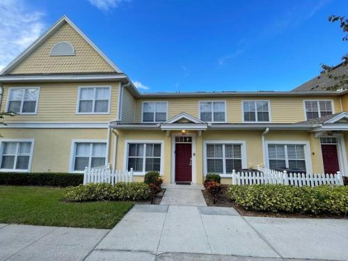 a yellow house with a white fence in front of it at Family Friendly 3BR near Disney in Kissimmee