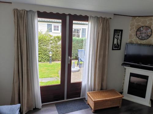 a living room with a sliding glass door with a television at Camping Vossenberg - op de Veluwe! in Epe