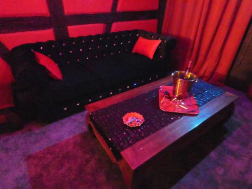 a living room with a black couch and a table at LOVE ROOM Le rouge et noir in Barr