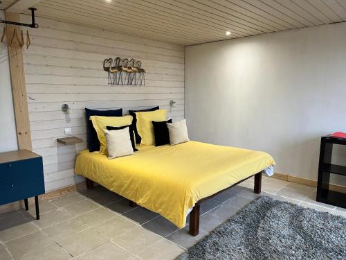 een slaapkamer met een bed met gele lakens en kussens bij Maxilly appart in Saint-Paul-en-Chablais