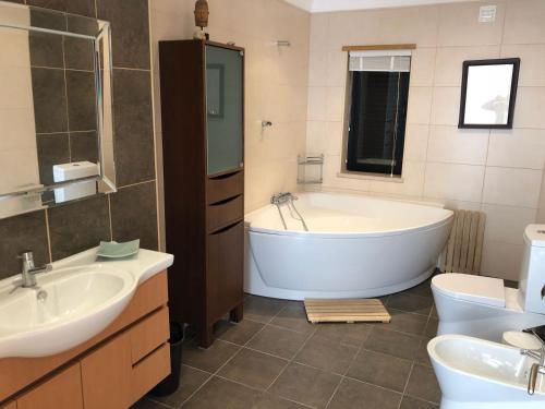 a bathroom with a tub and a sink and a toilet at VILLA Casa Eden in Vila Nova De Cacela