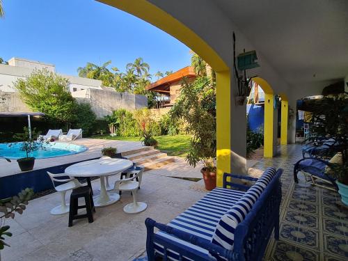 un patio con mesa, sillas y piscina en Casa pé na areia, en Guarujá