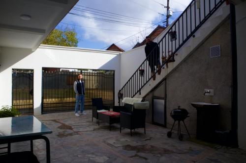 a woman standing on a patio next to a staircase at GOT Prishtina Hostel in Pristina