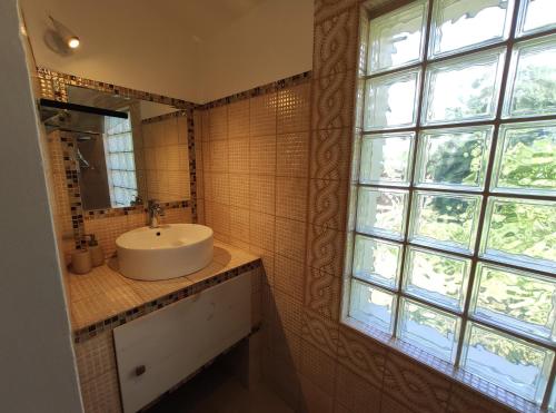 une salle de bain avec un lavabo et une grande fenêtre dans l'établissement La Petite Maison Neuvecelle - Maison de village, à Neuvecelle