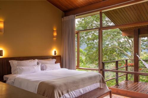 1 dormitorio con cama y ventana grande en Pousada do Cedro, en Santo Antônio do Pinhal