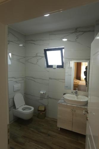 een badkamer met een toilet, een wastafel en een tv bij Vila Ndrio in Pogradec