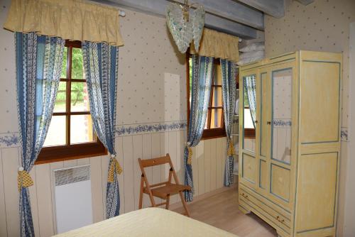 a bedroom with a bed and a chair and windows at Le Clos du Rossignol in Le Tartre