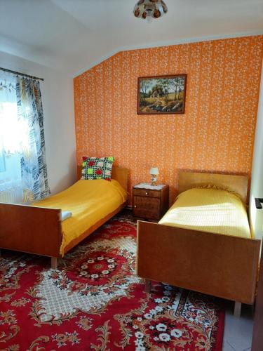 2 bedden in een kamer met oranje behang bij Stylowe PRLove in Rogowo