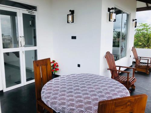 a dining room with a table and chairs and windows at Indika's Apartment in Hikkaduwa