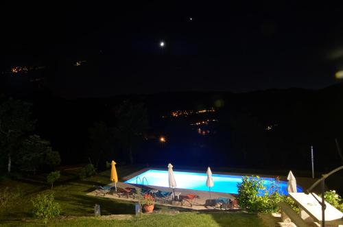 a swimming pool at night with umbrellas at Cantinho da Pedra in Vieira do Minho