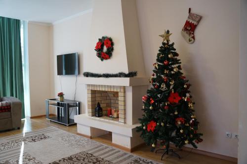 a christmas tree in a living room with a fireplace at Raduga West Pineforest - коттедж в аренду на Иссык-Куле in Koshkolʼ