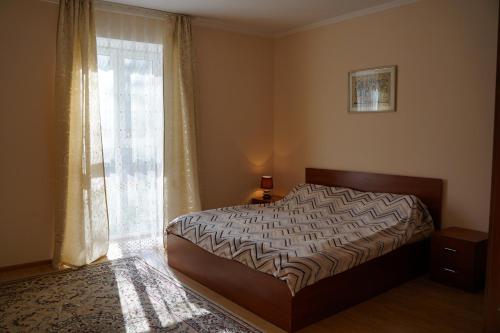- une chambre avec un lit et une grande fenêtre dans l'établissement Raduga West Pineforest - коттедж в аренду на Иссык-Куле, à Koshkolʼ
