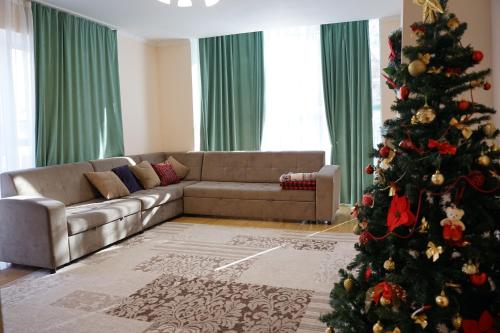 a living room with a christmas tree and a couch at Raduga West Pineforest - коттедж в аренду на Иссык-Куле in Koshkolʼ