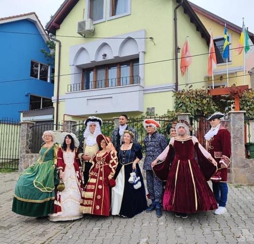 un grupo de personas vestidas con ropa histórica parada frente a un edificio en Cosbuc Residence & Villa, en Sighişoara