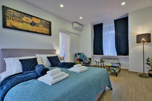 - une chambre avec un lit bleu et blanc et une chaise dans l'établissement Aurea City Center Apartment Zagreb, à Zagreb