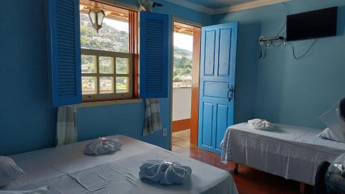 Habitación azul con 2 camas y ventana en Pousada Ouro Preto, en Ouro Preto