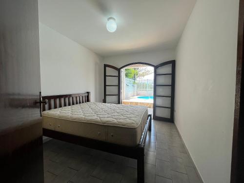 ein Schlafzimmer mit einem Bett und einem offenen Fenster in der Unterkunft Casa com piscina Praia de Leste in Pontal do Paraná