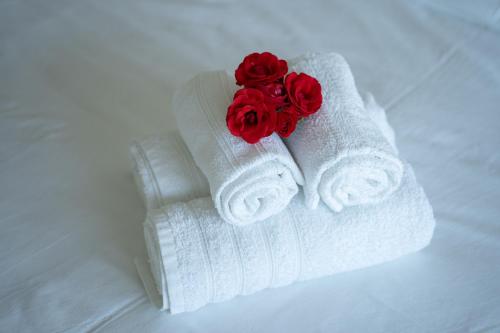 duas toalhas brancas com rosas vermelhas numa cama em Cantinho da Pedra em Vieira do Minho
