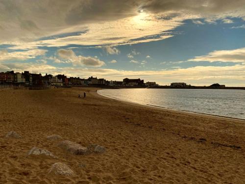 a beach with people walking on the sand and the water at Swift Retreat Caravan - Morecambe in Morecambe