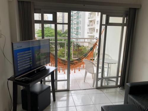 a living room with a computer on a table and a balcony at Relax Pitangueiras Guarujá in Guarujá