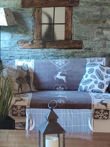 a blue couch with pillows and a candle on a table at Il nido di Lele e Schina in Arvier
