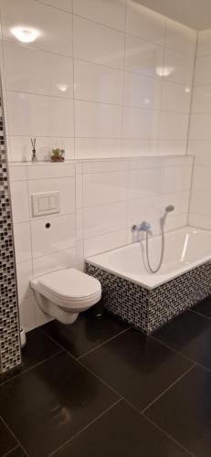 La salle de bains blanche est pourvue de toilettes et d'une baignoire. dans l'établissement Homey Apartments Harbor Suite - Parking Two Bathrooms Netflix Sea view, à Bremerhaven
