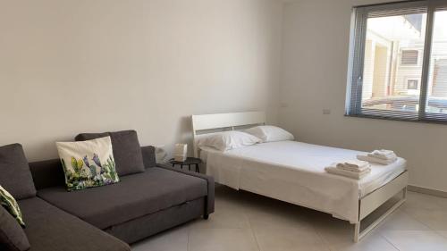 a bedroom with a bed and a couch and a window at Carolina Apartments - Monolocale in Capo dʼOrlando