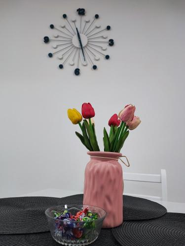 a pink vase with flowers and a bowl of candy at White pearl & SPA in Veliko Gradište