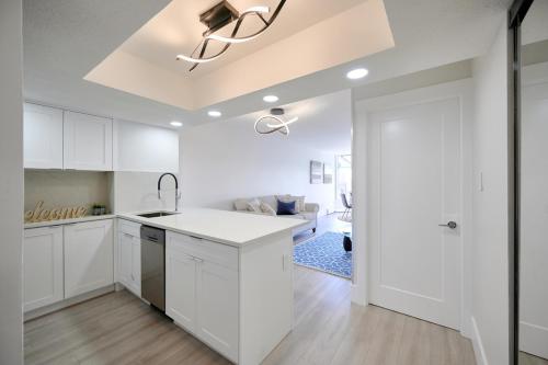 a kitchen with white cabinets and a living room at Drake950 in Vancouver