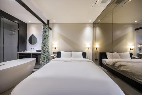 首爾的住宿－Hotel Lemong，一间卧室设有两张床、一个浴缸和一个水槽