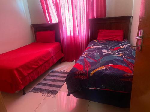 a bedroom with two beds with red sheets and a window at Toke homestay nr 37 omatjene street Cimbabacia in Academia