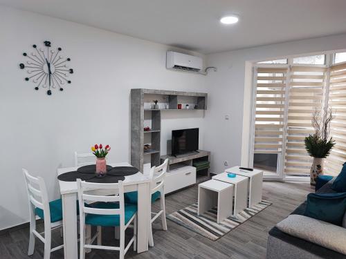 a white living room with a table and chairs and a tv at White pearl & SPA in Veliko Gradište