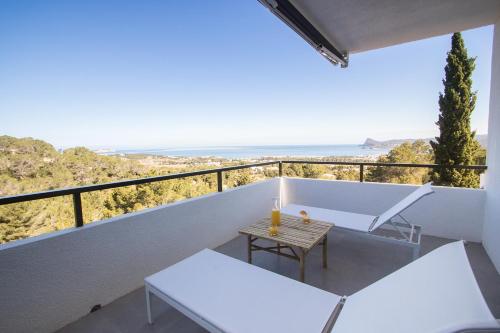 a balcony with white furniture and a view of the ocean at Casa Victoria Suites in Sant Josep de sa Talaia